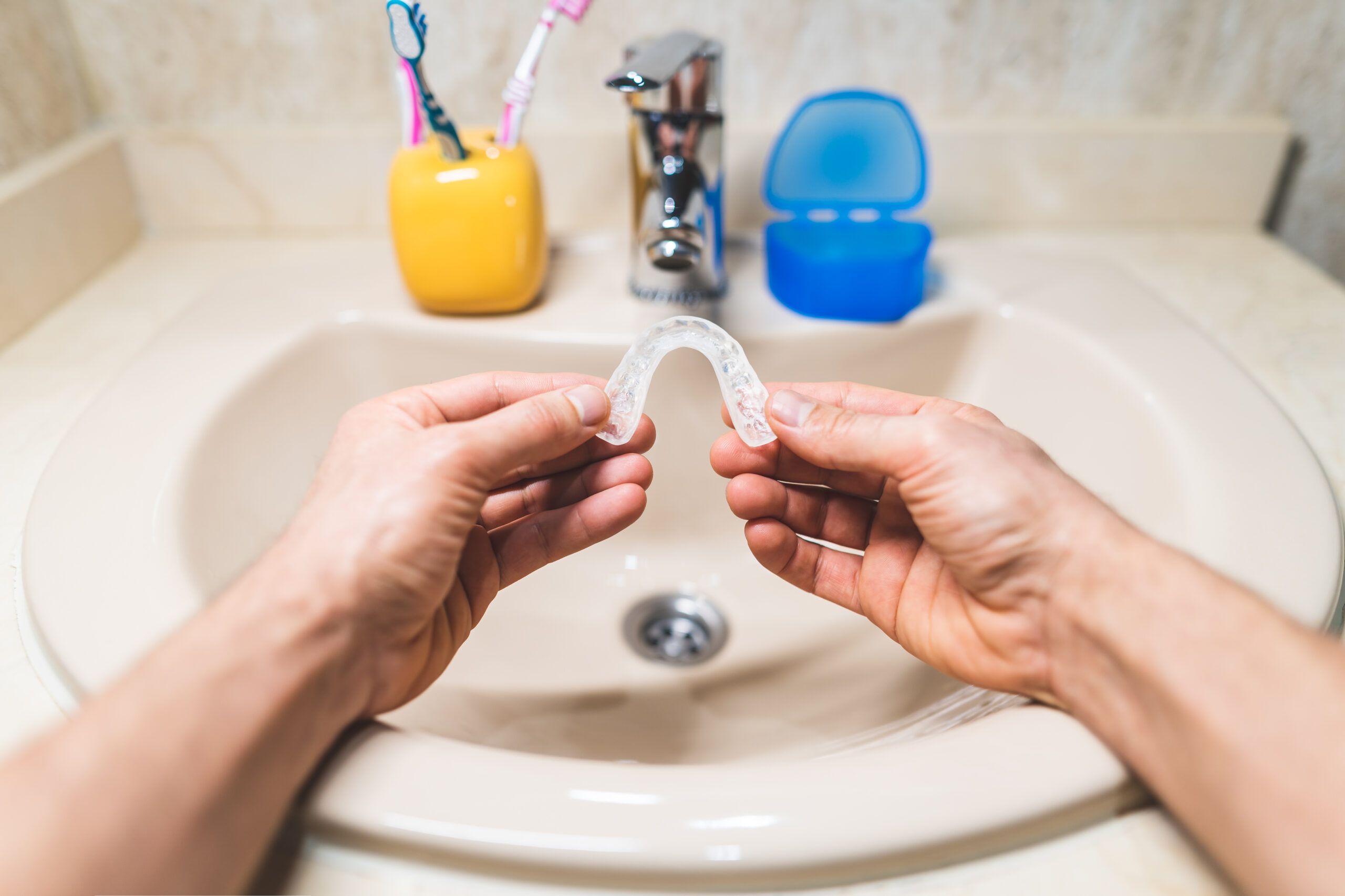 woman holding her night guard over the sink