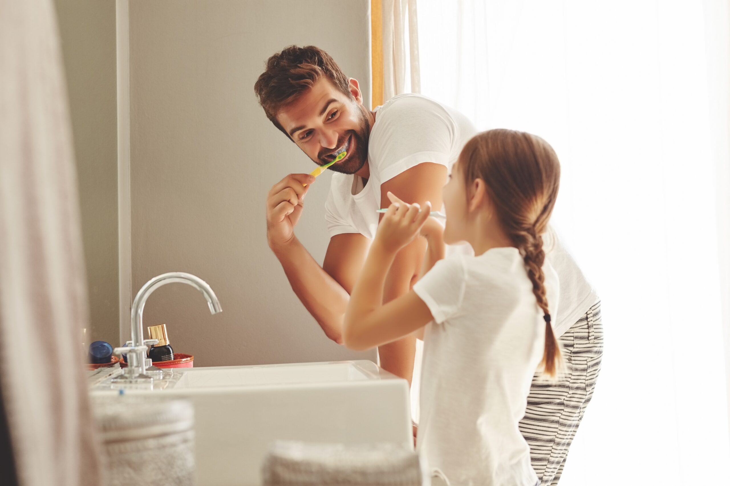 father and daughter brushing their teeth together