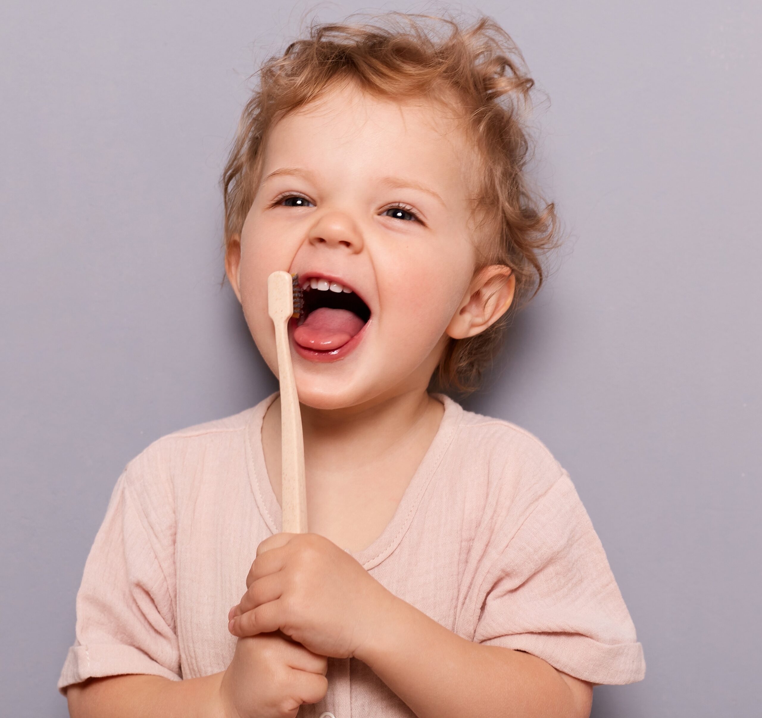 young child holding toothbrush up to mouth